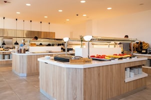 Un moderno montaje tipo buffet con múltiples estaciones de servicio, una variedad de alimentos y una decoración interior limpia y contemporánea.