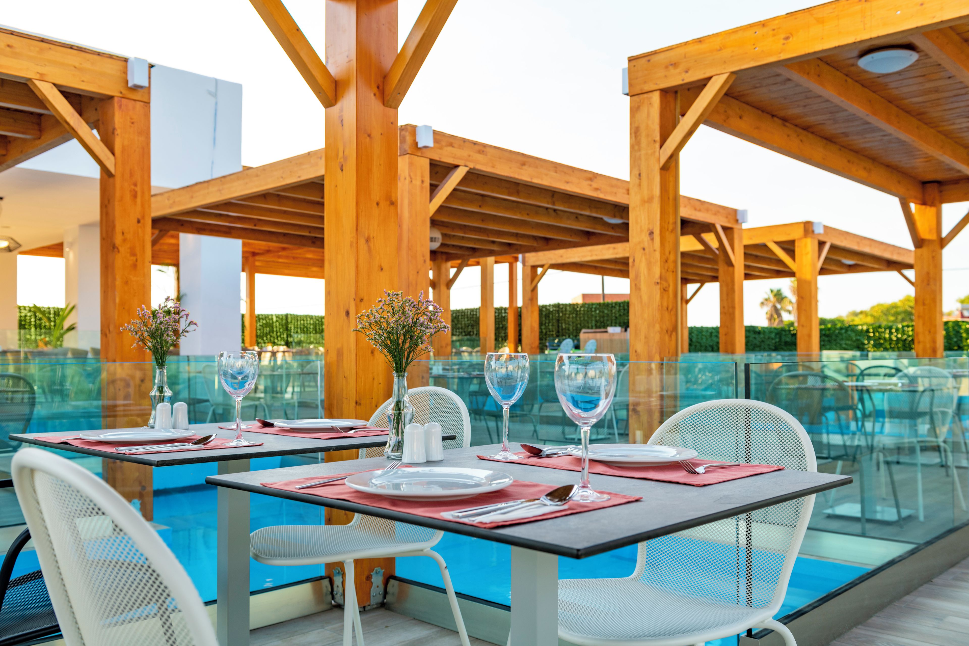 Un espace extérieur aménagé pour les repas, avec des tables et des chaises, une piscine et des pergolas en bois.