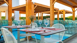 Un espace extérieur aménagé pour les repas, avec des tables et des chaises, une piscine et des pergolas en bois.