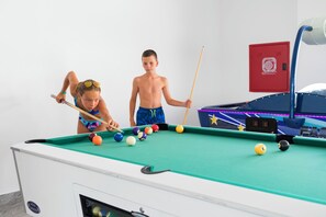 A pool table with balls and cues, a red fire extinguisher, and a pool table cabinet. - Lambi Resort (Kos)