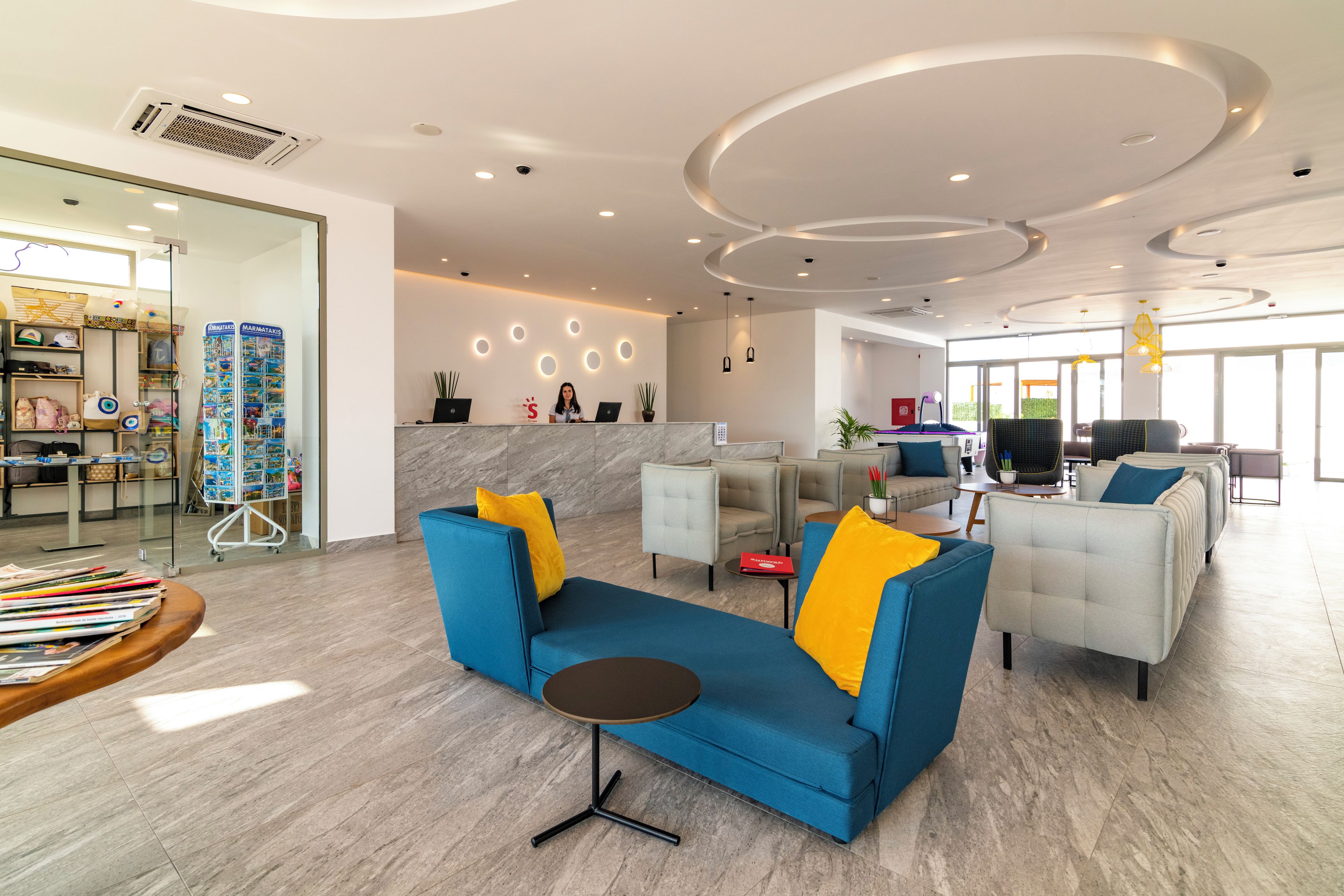 Een moderne hotelentree met een receptiebalie, een zithoek en een eetgedeelte.