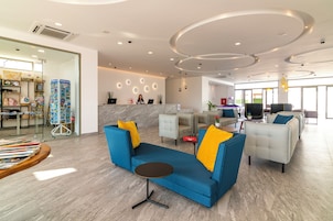 Un vestíbulo moderno de hotel con una recepción, área de estar y un espacio para comer.