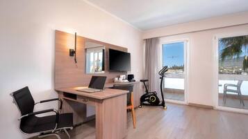 Une chambre d’hôtel équipée d’un bureau, d’une chaise, d’un tapis de course et d’une grande fenêtre donnant sur un beau paysage.