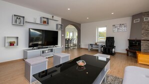 Una sala de estar moderna con un televisor de pantalla plana grande, una mesa de centro y una chimenea.