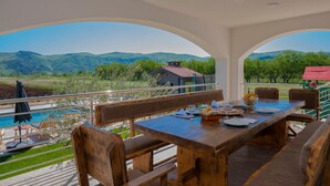 Una mesa de madera con sillas y vistas a un paisaje montañoso.