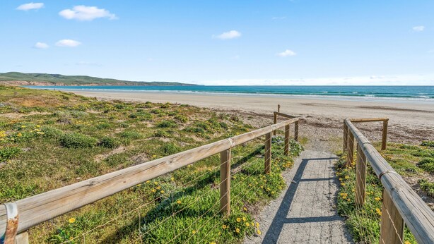 A wooden pathway leading to a beach with a clear view of the ocean.