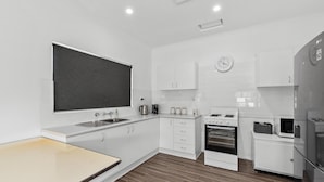 A modern kitchen with white cabinets, a blackboard, a sink, a stove, and a microwave.