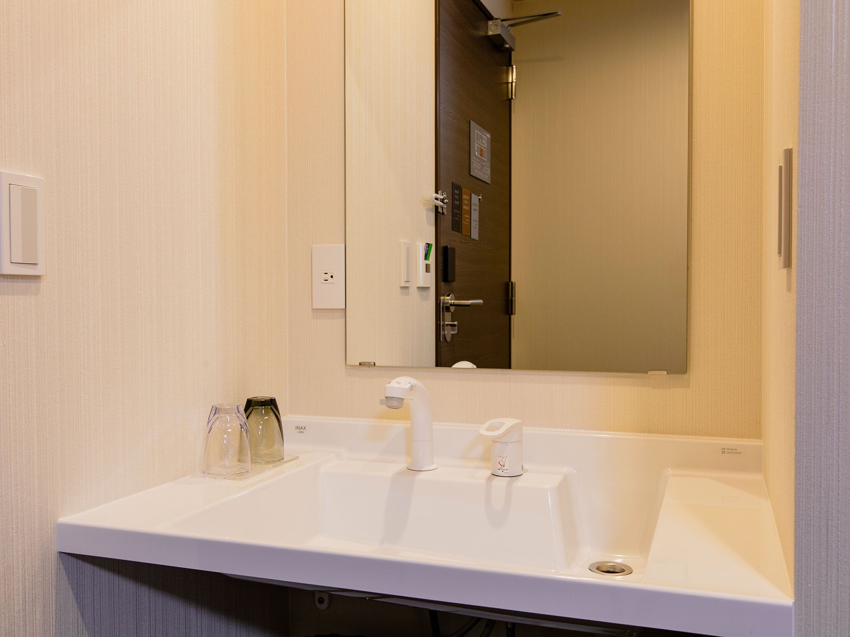 A bathroom with a white sink, a mirror, and a door with a handle.