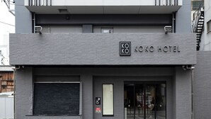 Un edificio moderno con un letrero que dice 'KOKO HOTEL' y un símbolo de accesibilidad para sillas de ruedas.