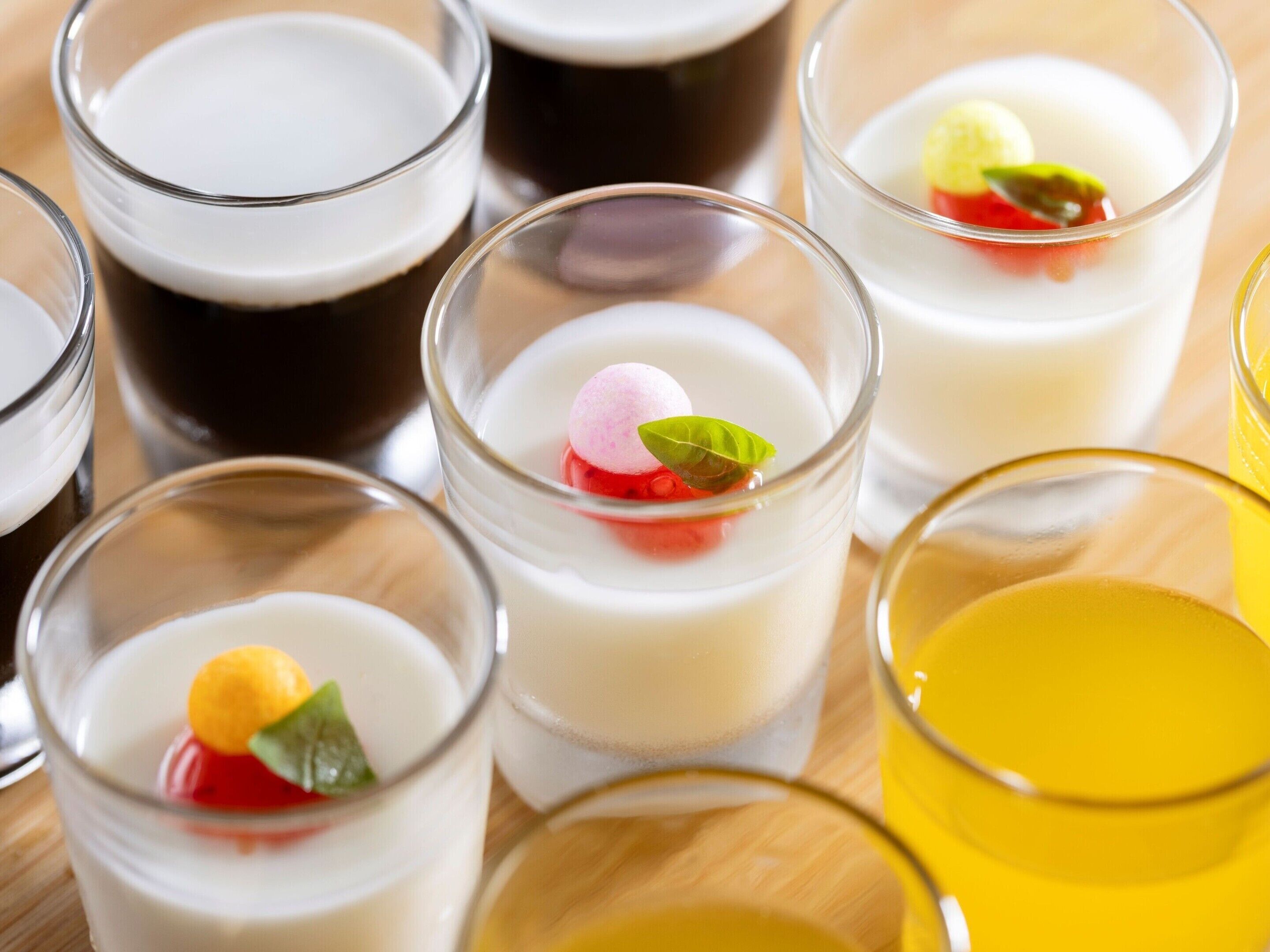 A variety of clear glass cups with different colored liquids and garnishes.