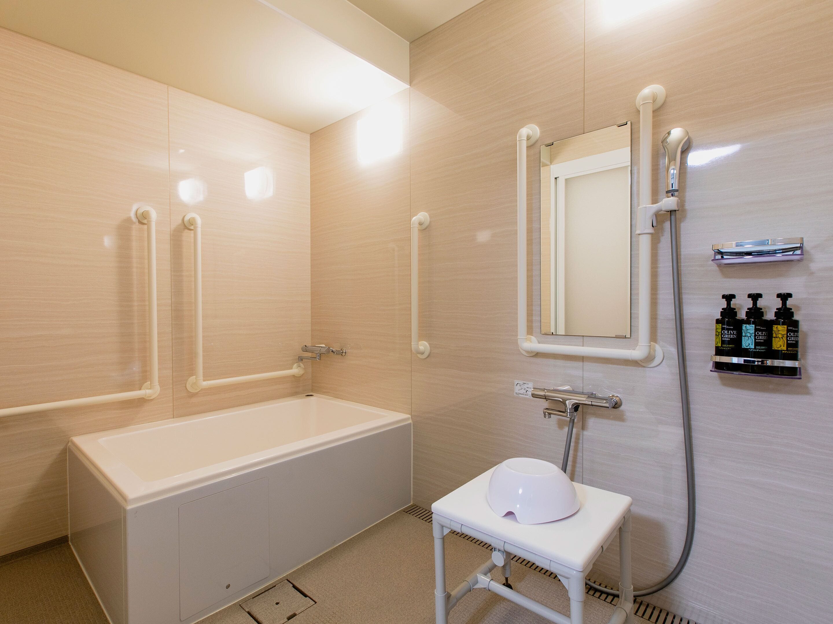 Un baño moderno con bañera, lavamanos, espejo y barras de apoyo.