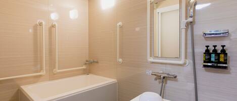 A modern bathroom with a bathtub, a sink, a mirror, and handrails.