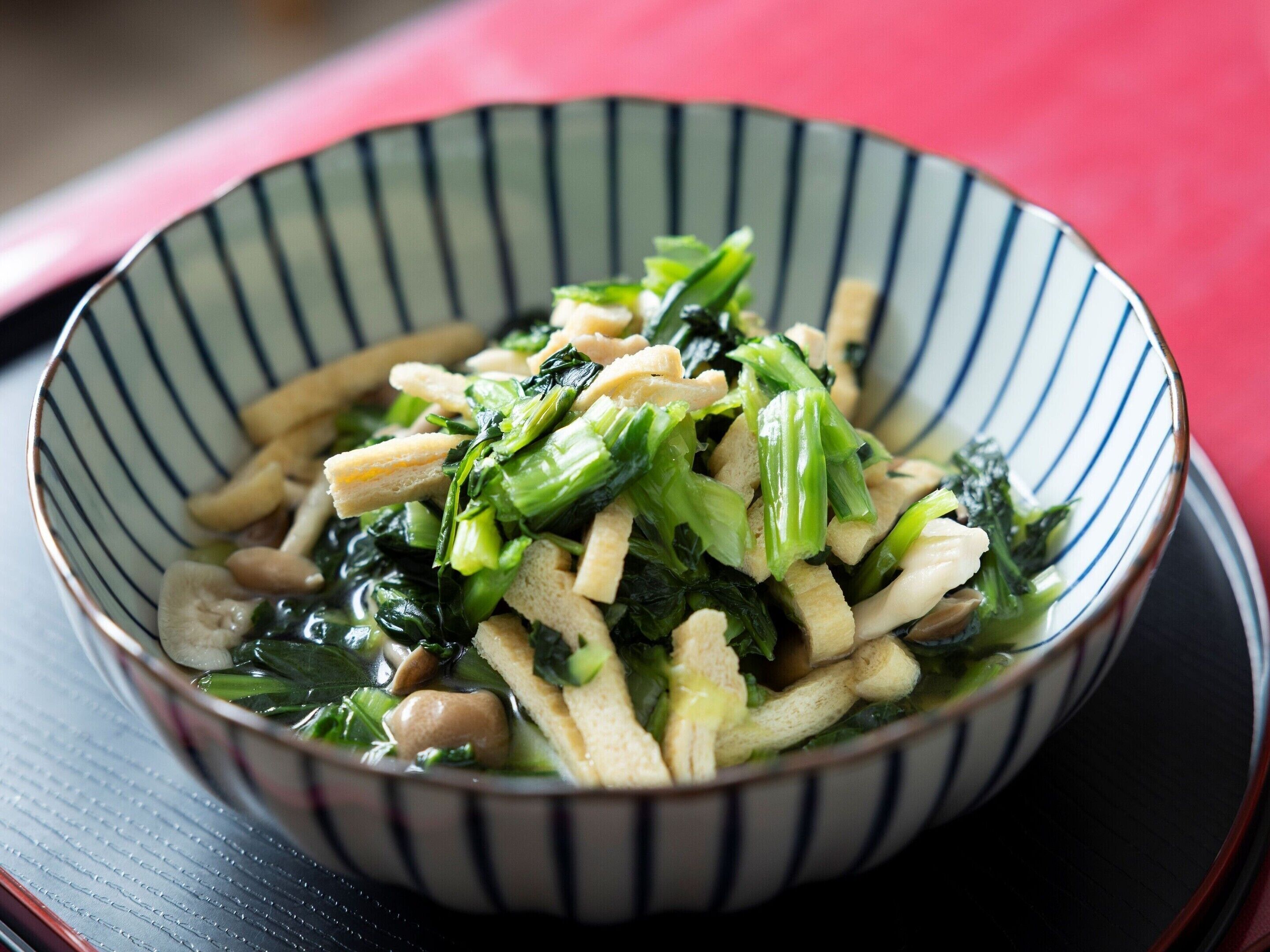 A bowl of stir-fried vegetables with tofu and mushrooms.