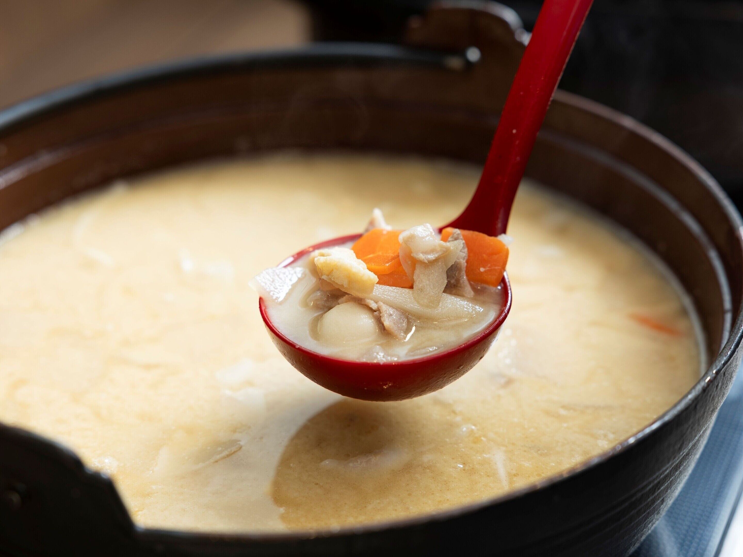 A bowl of soup with a red spoon.