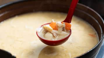 A bowl of soup with a red spoon.