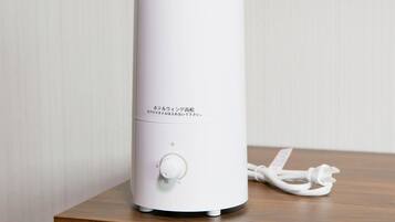 A white cylindrical device with a control knob and a power cord on a wooden surface.