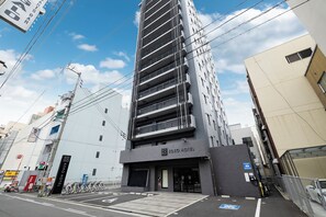 Un edificio moderno con un cartel que dice Koko Hotel, varios pisos y un estacionamiento con bicicletas.