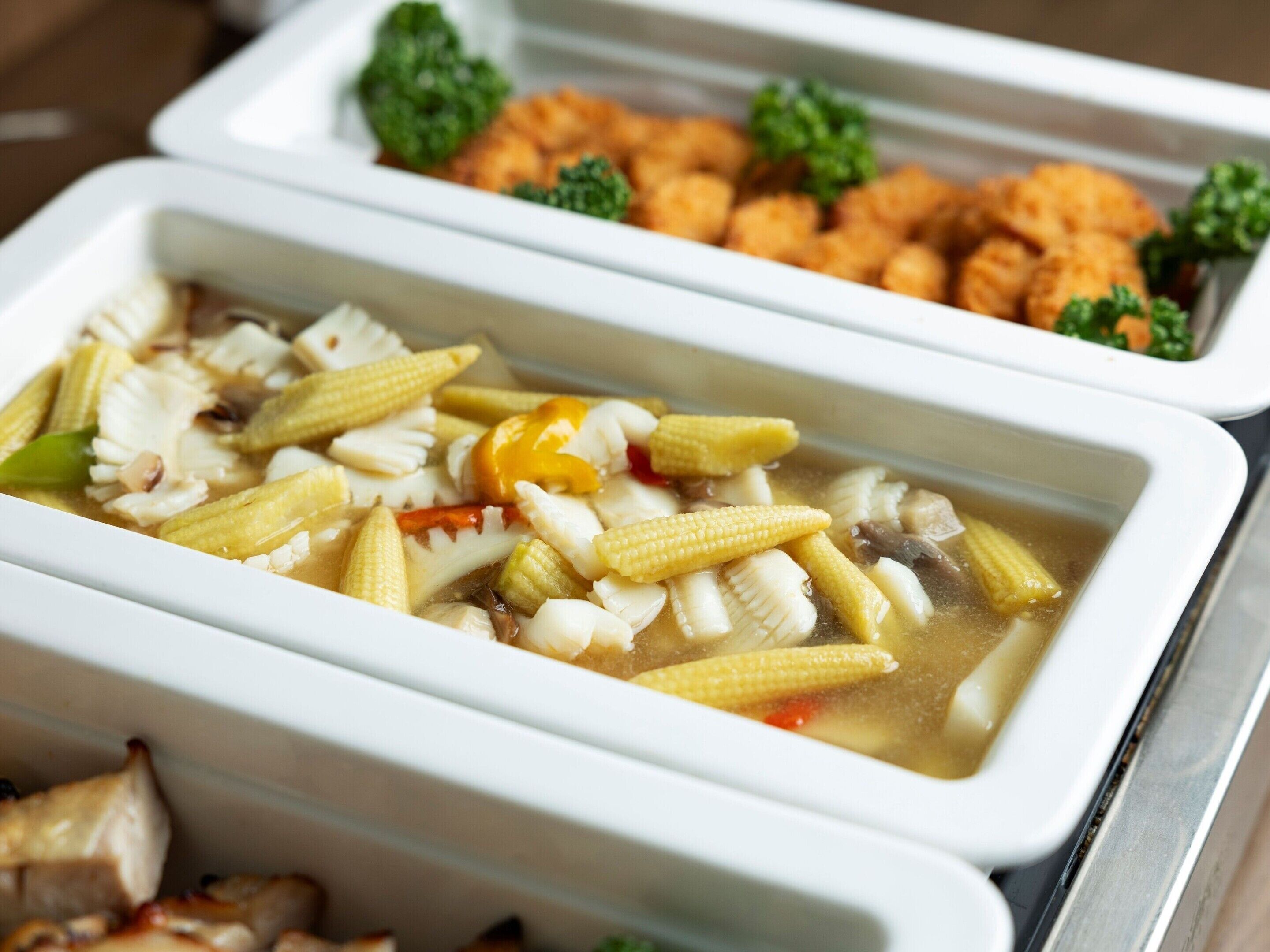 A meal with corn and vegetables in a white bowl.