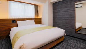 Habitación de hotel con una cama grande, una ventana con cortinas translúcidas, una pared oscura con textura y un espejo.