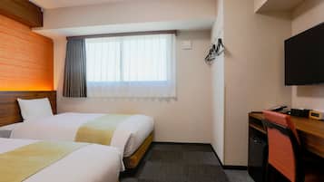 Habitación de hotel con dos camas, un escritorio con silla, televisor y ventana con cortinas.