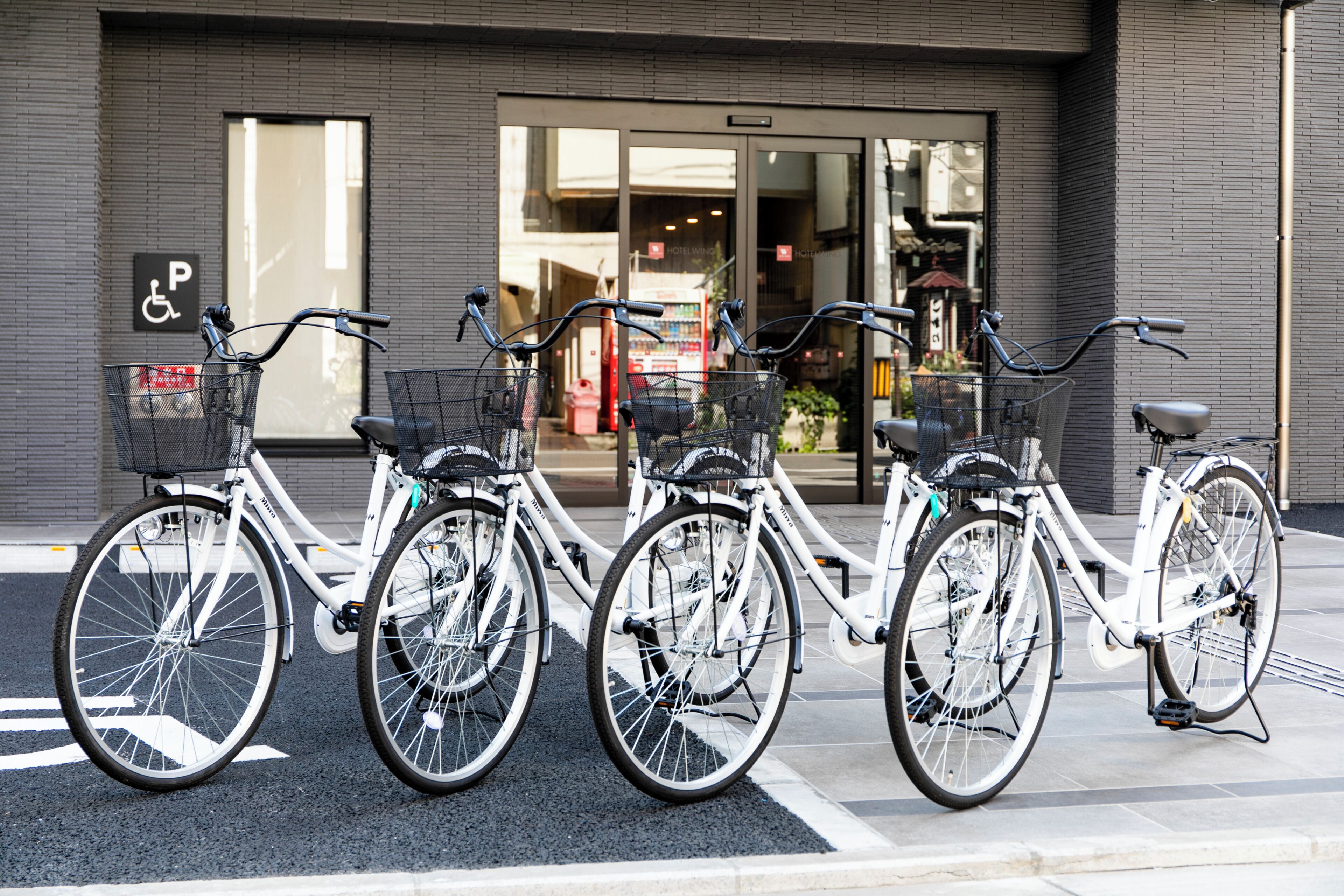 A row of bicycles parked in front of a building with a visible handicapped parking sign.