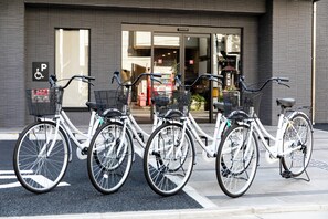 Varias bicicletas estacionadas frente a un edificio con señal de estacionamiento para discapacitados.