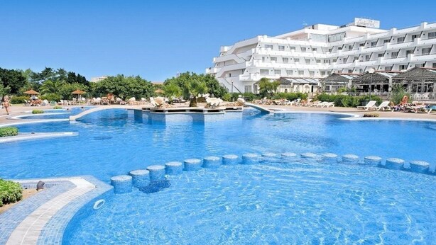A large swimming pool with a modern hotel in the background. - Hotel Mariant Park (Sant Llorenc des Cardassar)