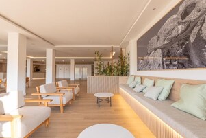 Un moderno vestíbulo de hotel con zona de estar, mostrador de recepción y una gran pared de roca.