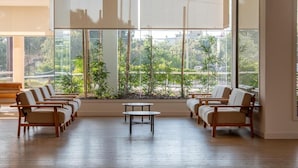 A room with a large window, wooden flooring, and a seating area with chairs and a table. - Hotel Mariant Park (Sant Llorenc des Cardassar)