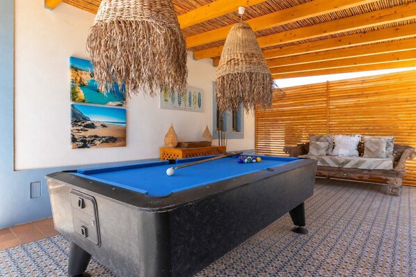 A pool table with balls, a sofa, and wall art in a room with wooden beams and a patterned floor. - Casa Polgoda, luxury villa with ocean views (Carvoeiro)