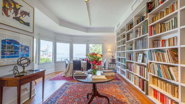 A spacious room with a large bookshelf, a dining area with a table and chairs, and a view of the outside through large windows. - 2 bedroom nice apartment in Cádiz (Cádiz)