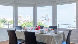 A dining area with a table set for four, large windows offering a view of a port and cityscape. - 2 bedroom nice apartment in Cádiz (Cádiz)