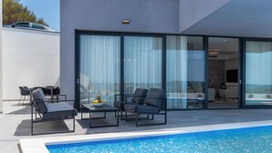 Ein moderner Poolbereich im Freien mit Liegestühlen und einem Esstisch.