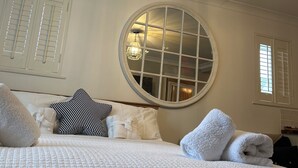 Ett hotellrum med en stor säng, en rund spegel och en taklampa.