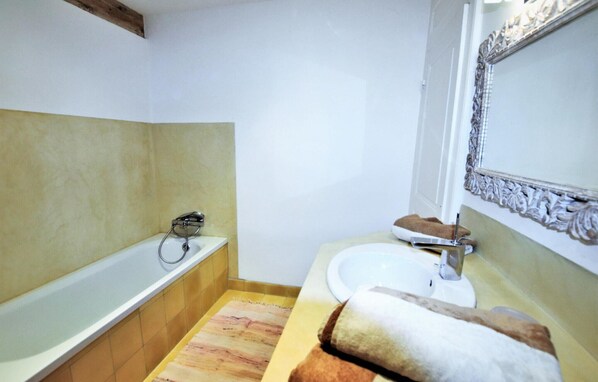 A bathroom with a bathtub, a sink, a mirror, and a towel. - Cozy home in Cliousclat with private swimming pool, can be inside or outside (Cliousclat)
