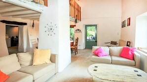 Un'ampia zona giorno con soffitto alto, un tavolo da pranzo e un divano con cuscini.