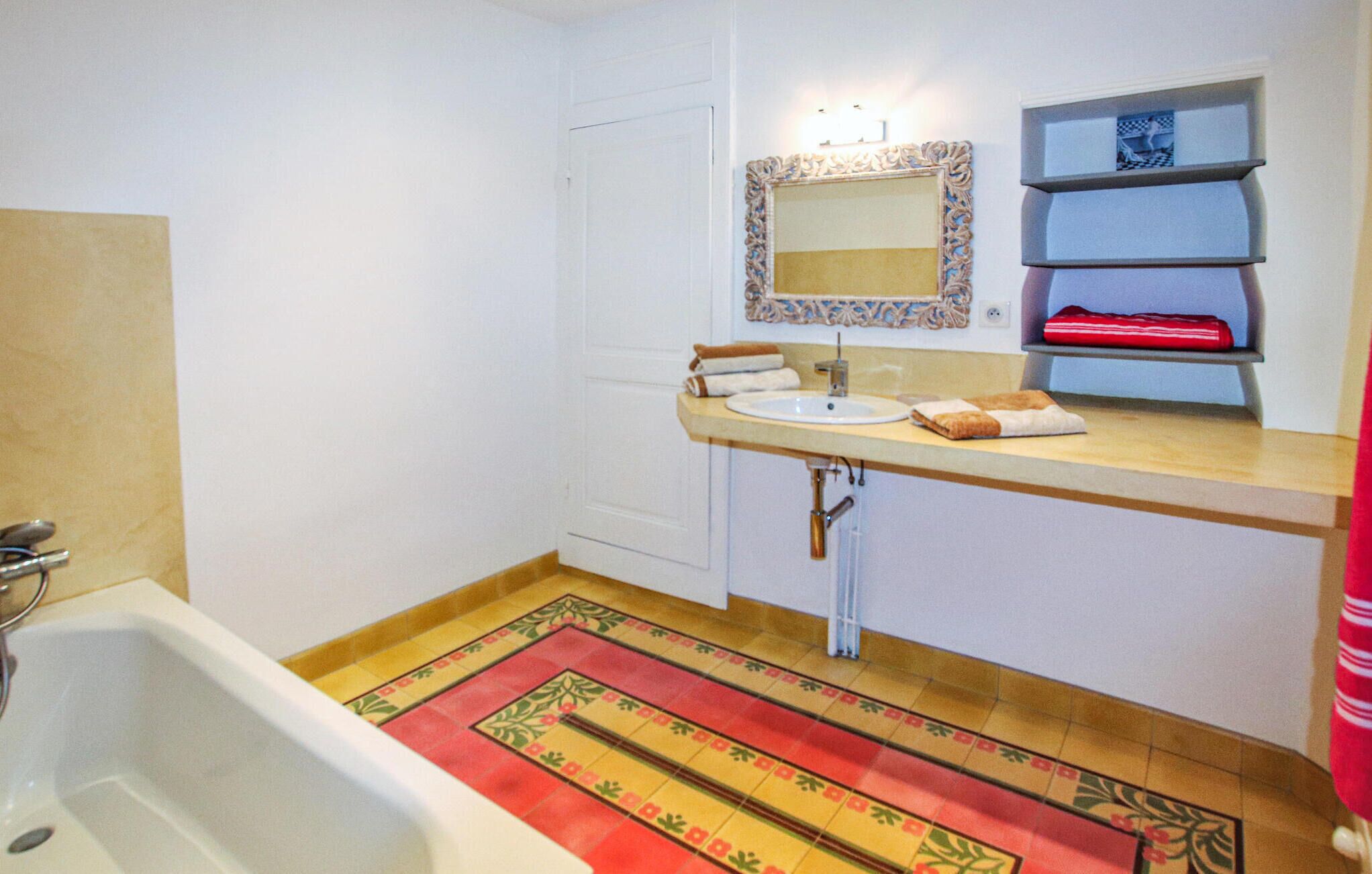 Ein Badezimmer mit Badewanne, Waschbecken, Spiegel und einem Ablagefach mit Handtüchern.
