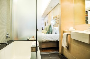 A modern bathroom with a bathtub, a shower area, and a vanity with a mirror.
