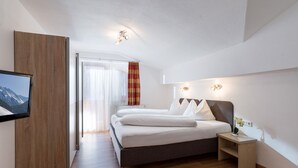 A modern hotel room with a large bed, a TV mounted on the wall, and a wooden floor. - Apartment mit 3 Schlafzimmern und Balkon (Gerlos)
