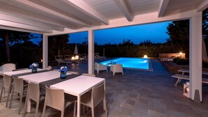 An outdoor patio with a pool, lounge chairs, and a dining area with tables and chairs. - Villa Ninetta 10+1, Emma Villas (Giulianova)