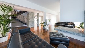 A modern living room with a black leather sofa, a coffee table, and a fireplace. There is a staircase leading to an upper level. - Villa Ninetta 10+1, Emma Villas (Giulianova)