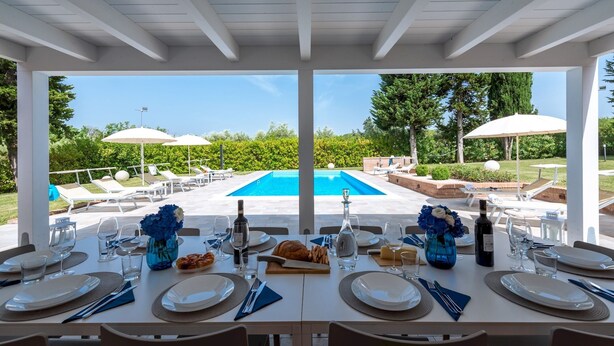 A dining area with a view of a swimming pool, outdoor seating, and umbrellas. - Villa Ninetta 10+1, Emma Villas (Giulianova)