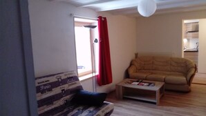 A living room with a sofa, a small table, and a red curtain.