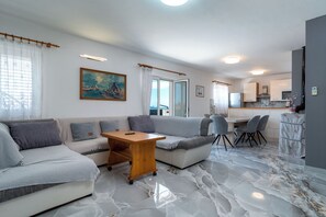 A modern living room with a sofa, a coffee table, and a dining area with chairs.