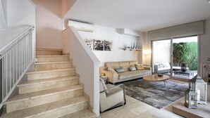 Ein modernes Wohnzimmer mit Treppe, einer Sofagarnitur und einem Couchtisch.
