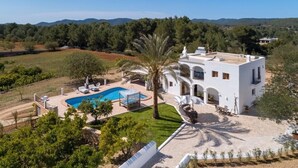 Uma villa moderna com piscina, rodeada por vegetação exuberante e montanhas ao fundo.