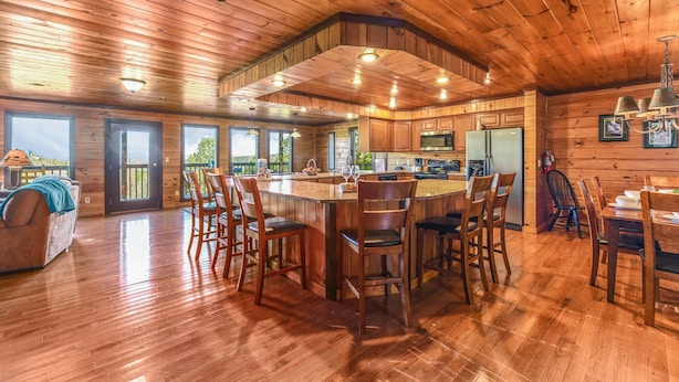 A spacious kitchen with wooden cabinets, a central island, and bar stools. - Summer Break! Hot Tub | Views | 4-Story MTN Cabin (Gatlinburg)