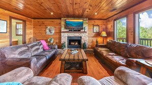 A cozy cabin interior with a stone fireplace, leather sofas, and a wooden ceiling. - Summer Break! Hot Tub | Views | 4-Story MTN Cabin (Gatlinburg)