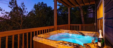 A hot tub with a wooden deck and a bottle of champagne.