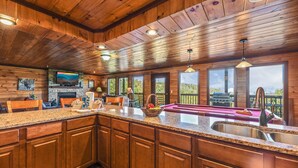 A spacious kitchen with wooden cabinets, granite countertops, and a large island with a sink. - Summer Break! Hot Tub | Views | 4-Story MTN Cabin (Gatlinburg)